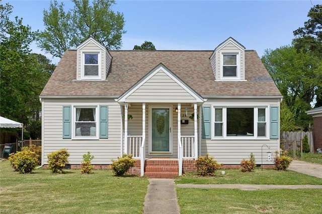 cape cod home featuring roof with shingles, crawl space, fence, and a front lawn