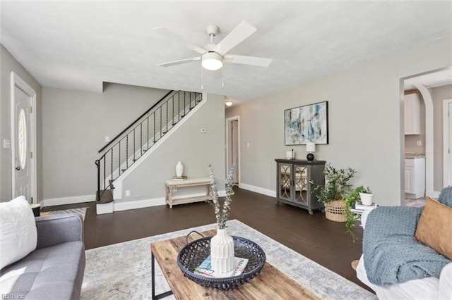 living room with stairway, ceiling fan, baseboards, and wood finished floors