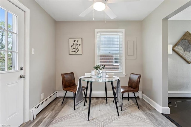 dining room featuring baseboards, a ceiling fan, wood finished floors, and baseboard heating