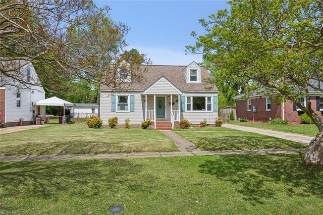 cape cod house featuring a front yard, fence, and a shingled roof