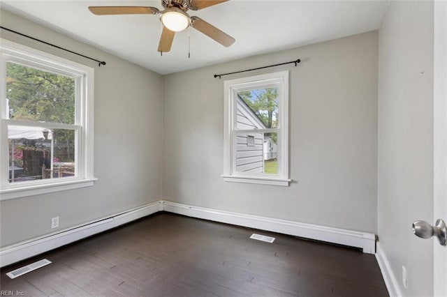 empty room with baseboards, a baseboard heating unit, dark wood-style floors, visible vents, and ceiling fan