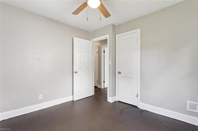 unfurnished bedroom with visible vents, baseboards, and dark wood finished floors