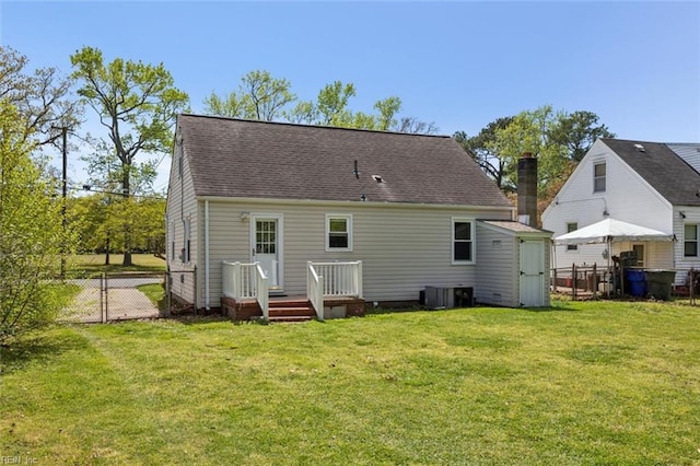 back of property with central AC unit, fence, a lawn, and a gate