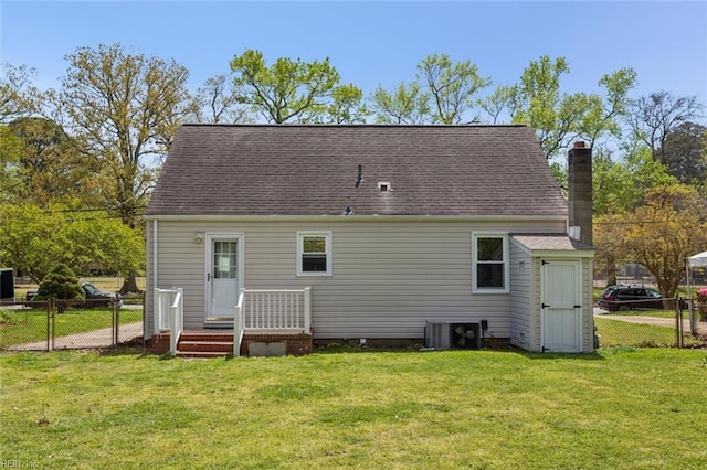 back of property with central AC, a yard, fence, and a chimney