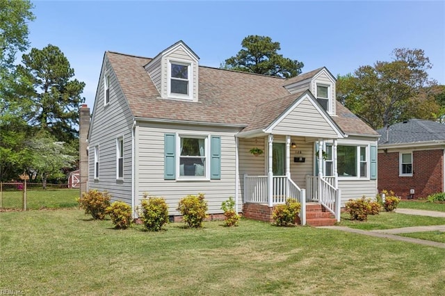 cape cod home with a shingled roof, fence, and a front lawn