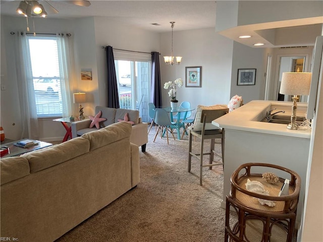 living area with carpet floors, plenty of natural light, and an inviting chandelier