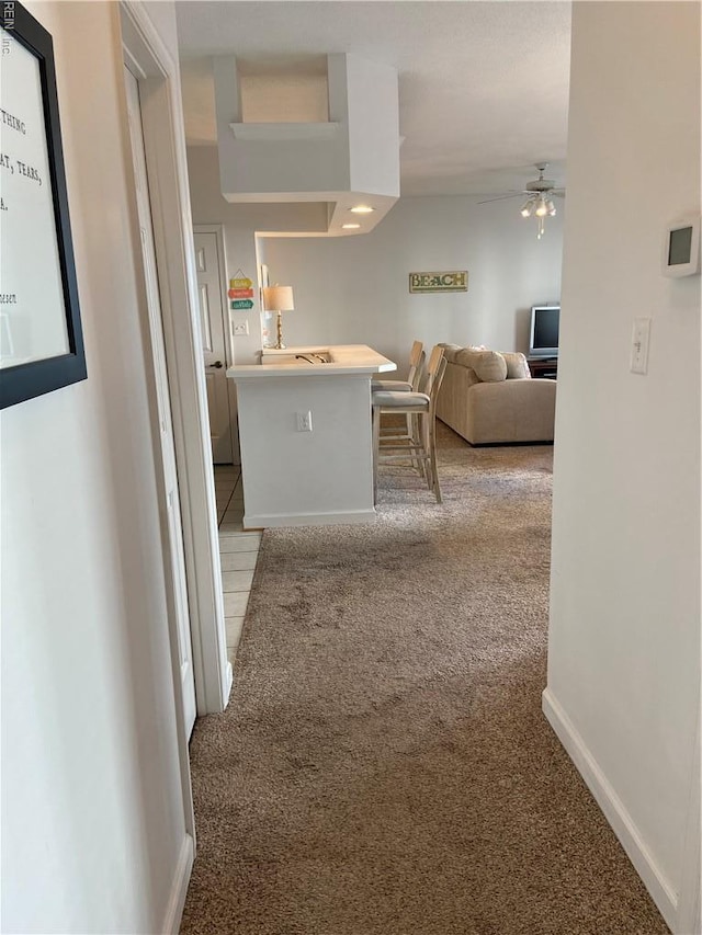 hall featuring light carpet and baseboards
