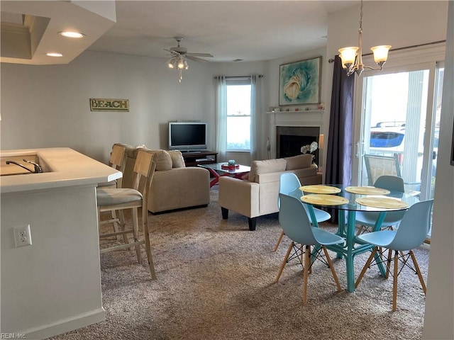 carpeted dining space featuring baseboards, recessed lighting, a fireplace, and ceiling fan with notable chandelier