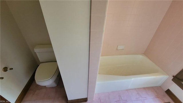 bathroom featuring tile patterned floors, a tub to relax in, and toilet