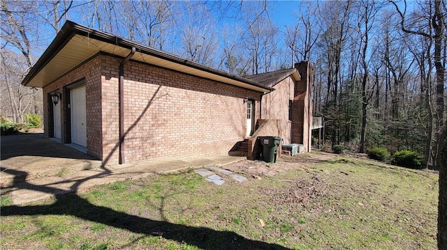 view of property exterior with a lawn, a chimney, a garage, and brick siding