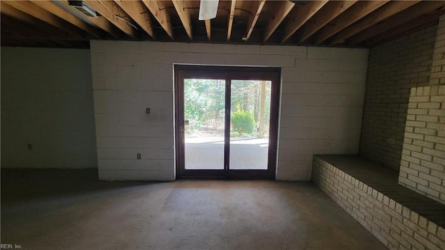 unfurnished living room featuring concrete floors and concrete block wall
