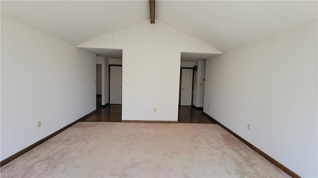 empty room featuring lofted ceiling with beams, carpet flooring, and baseboards