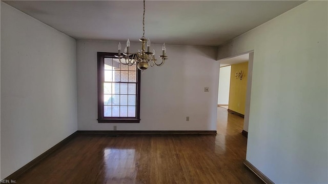 unfurnished dining area with dark wood-style floors, baseboards, and an inviting chandelier