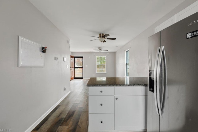 kitchen with dark wood finished floors, a ceiling fan, white cabinets, stainless steel fridge, and baseboards