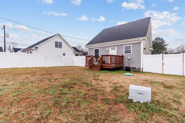 rear view of property featuring a shingled roof, a deck, a fenced backyard, and a lawn