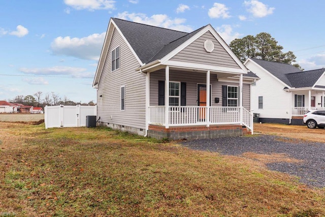 view of front of house featuring a front yard, central AC unit, covered porch, crawl space, and fence
