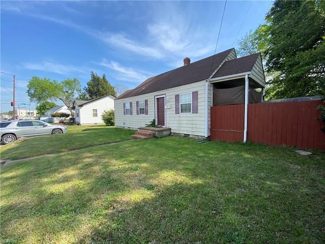 bungalow with a front lawn, fence, a shingled roof, and a chimney