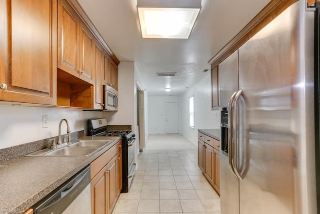 kitchen featuring light tile patterned floors, brown cabinetry, visible vents, a sink, and stainless steel appliances