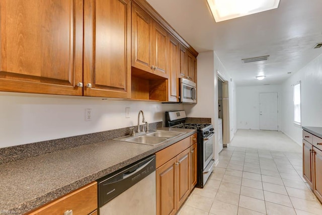kitchen featuring dark countertops, visible vents, brown cabinets, stainless steel appliances, and a sink