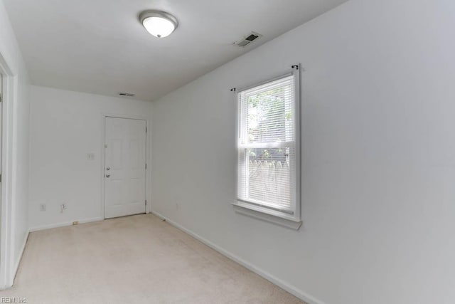 empty room featuring light colored carpet, baseboards, and visible vents