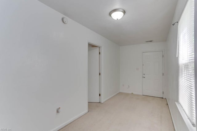 unfurnished room with visible vents, baseboards, and light colored carpet