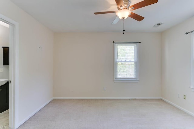 empty room with baseboards, light colored carpet, ceiling fan, and visible vents