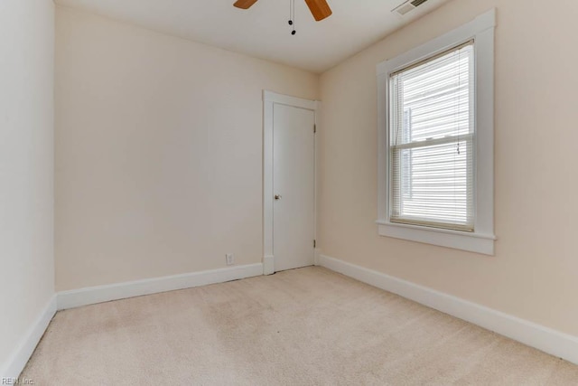 carpeted spare room with visible vents, baseboards, and ceiling fan