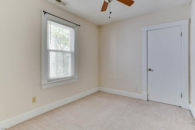 carpeted spare room featuring plenty of natural light, visible vents, baseboards, and ceiling fan