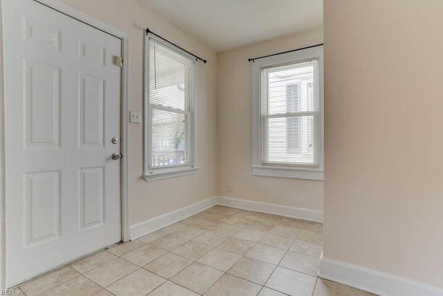 foyer featuring plenty of natural light, baseboards, and light tile patterned flooring