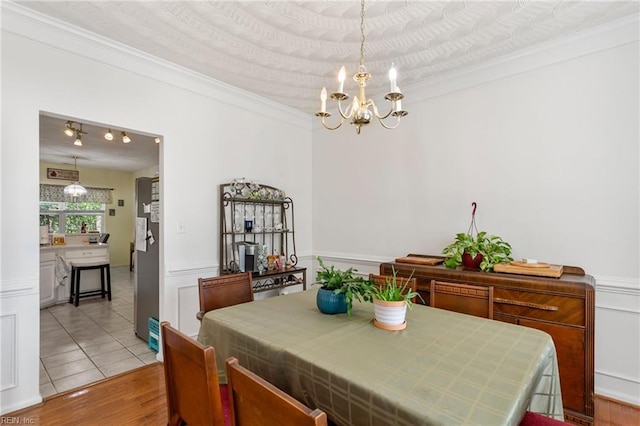 106 Elm Tree Ct, Suffolk, VA 23435 - dining area featuring light wood-style flooring, crown molding, an inviting chandelier, and a wainscoted wall