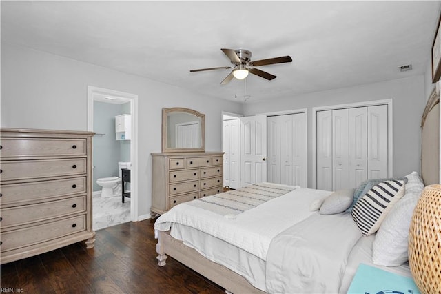 bedroom featuring multiple closets, ceiling fan, baseboards, ensuite bath, and dark wood-style floors
