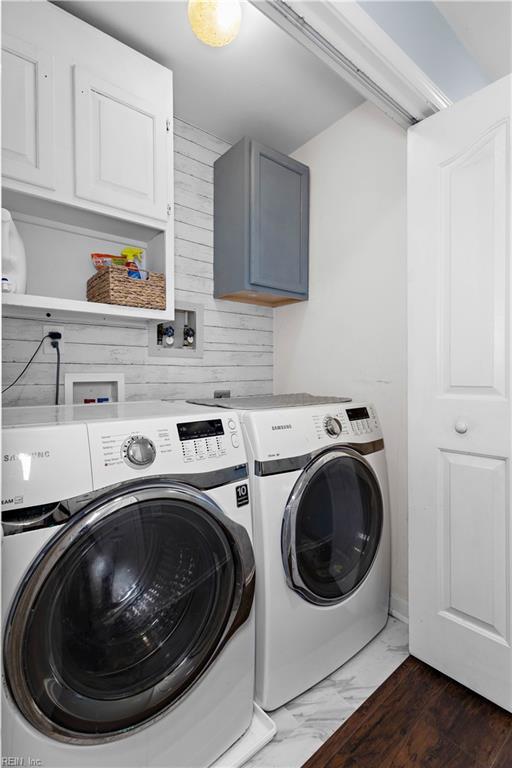 clothes washing area featuring separate washer and dryer, marble finish floor, and cabinet space