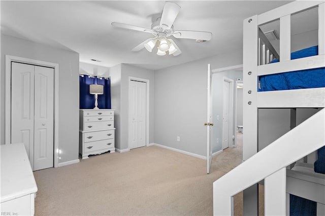 unfurnished bedroom with visible vents, baseboards, ceiling fan, multiple closets, and carpet floors