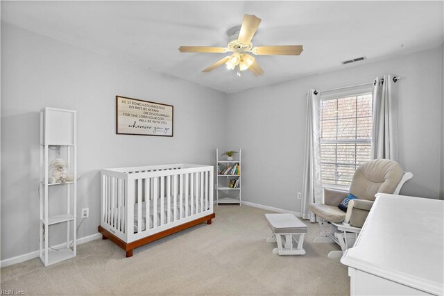 carpeted bedroom with a nursery area, visible vents, baseboards, and ceiling fan