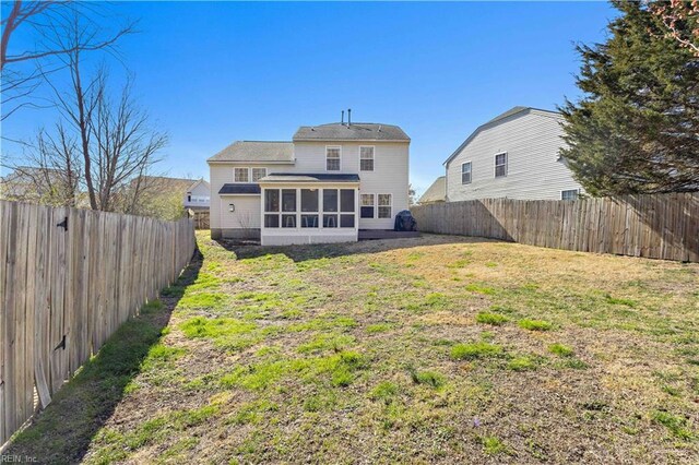 back of house with a lawn, a fenced backyard, and a sunroom