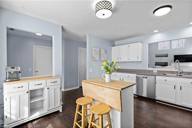 kitchen with white cabinets, a sink, dark wood finished floors, butcher block countertops, and dishwasher