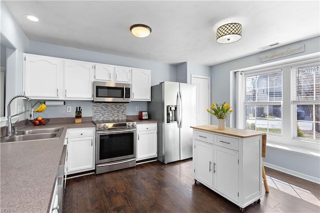 kitchen with white cabinets, dark wood finished floors, stainless steel appliances, and a sink