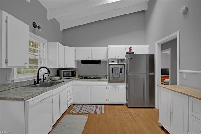 kitchen with white cabinets, stainless steel appliances, a sink, and high vaulted ceiling