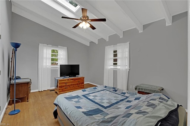 bedroom with ceiling fan, baseboards, vaulted ceiling with skylight, and light wood finished floors