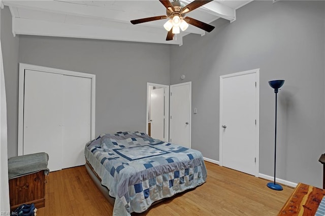 bedroom featuring ceiling fan, baseboards, wood finished floors, and vaulted ceiling with beams