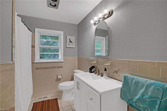 full bathroom featuring tile patterned floors, visible vents, toilet, tile walls, and wainscoting