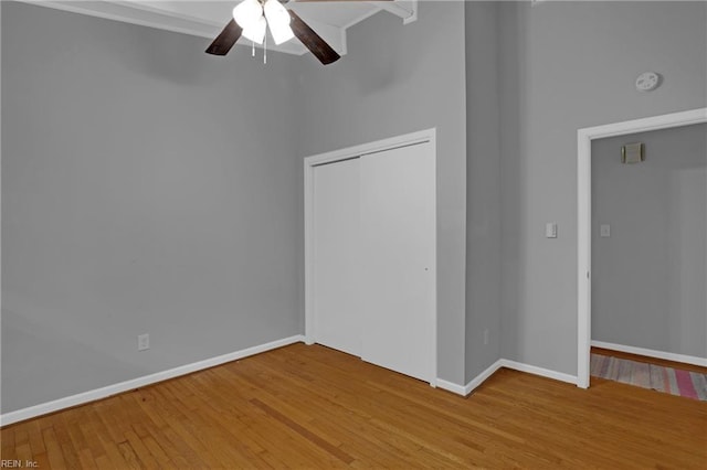 interior space featuring wood finished floors, ornamental molding, a closet, baseboards, and ceiling fan
