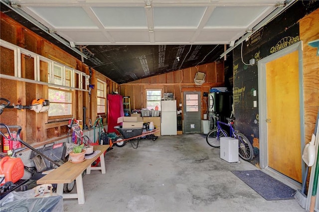 garage featuring wooden walls and freestanding refrigerator