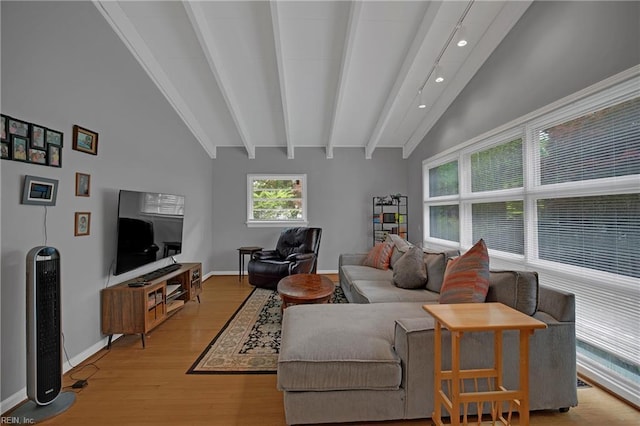 living area featuring light wood-style floors, vaulted ceiling with beams, and baseboards