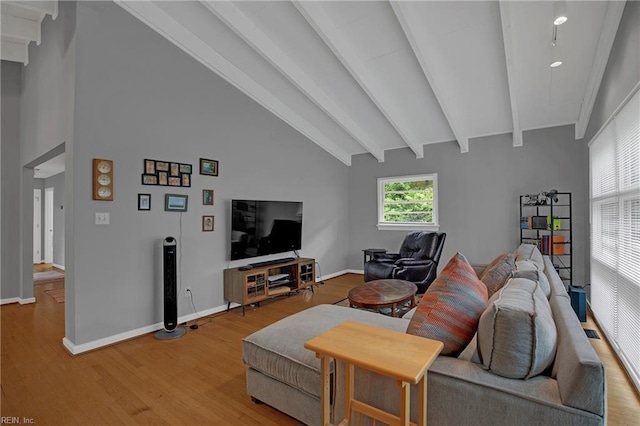 living area featuring vaulted ceiling with beams, light wood-style flooring, and baseboards