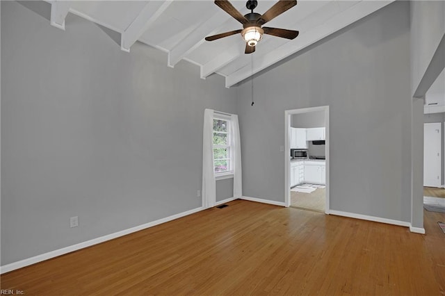 unfurnished room featuring beam ceiling, baseboards, a ceiling fan, wood finished floors, and high vaulted ceiling