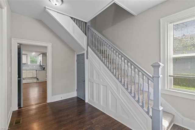 stairway with baseboards, visible vents, and wood finished floors