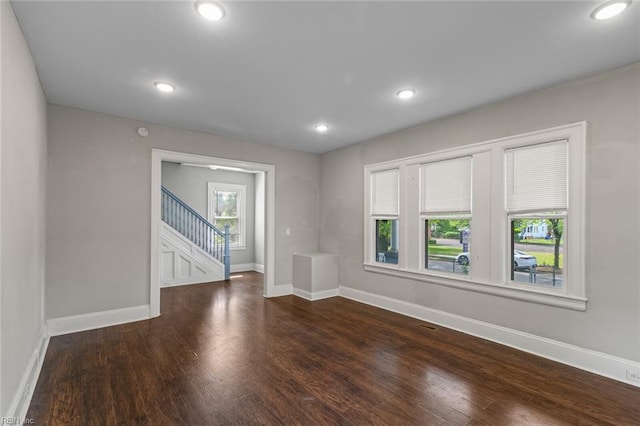 unfurnished room featuring baseboards, stairway, wood finished floors, and recessed lighting