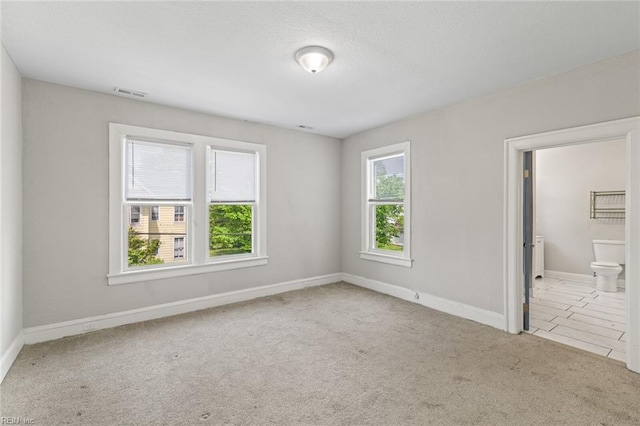 unfurnished bedroom featuring visible vents, connected bathroom, baseboards, and carpet floors