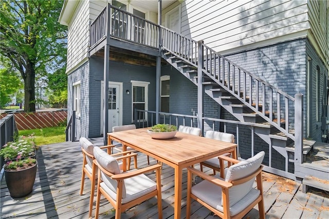 wooden terrace featuring fence, outdoor dining space, and stairs